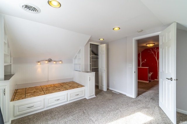 interior space featuring lofted ceiling, light carpet, and visible vents
