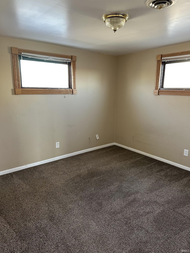 carpeted empty room featuring visible vents, baseboards, and a wealth of natural light