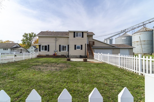 rear view of house featuring a yard, fence private yard, and a garage