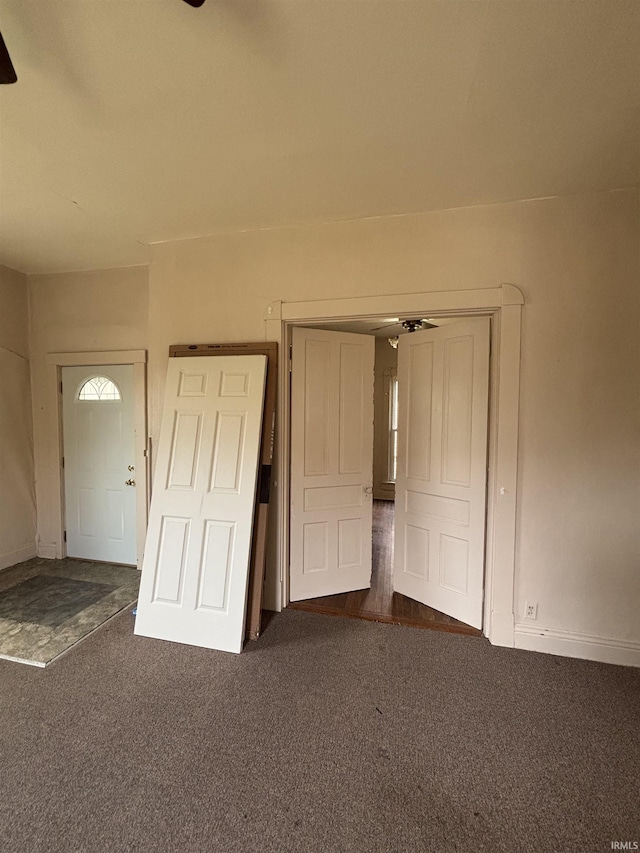 interior space featuring baseboards and dark colored carpet