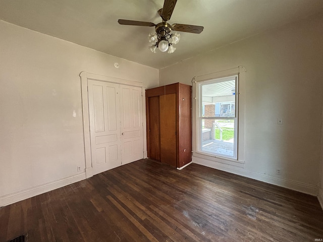 unfurnished bedroom featuring dark wood finished floors, baseboards, and ceiling fan