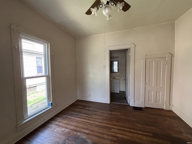spare room featuring dark wood-style floors, a sink, visible vents, baseboards, and a ceiling fan