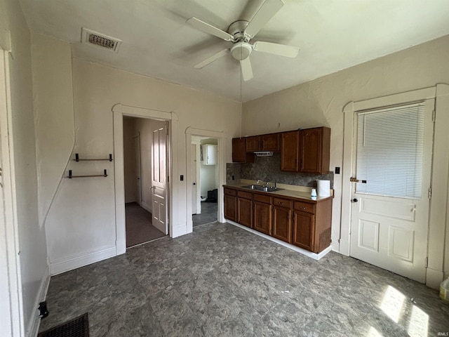 kitchen featuring a sink, visible vents, brown cabinetry, ceiling fan, and dark floors