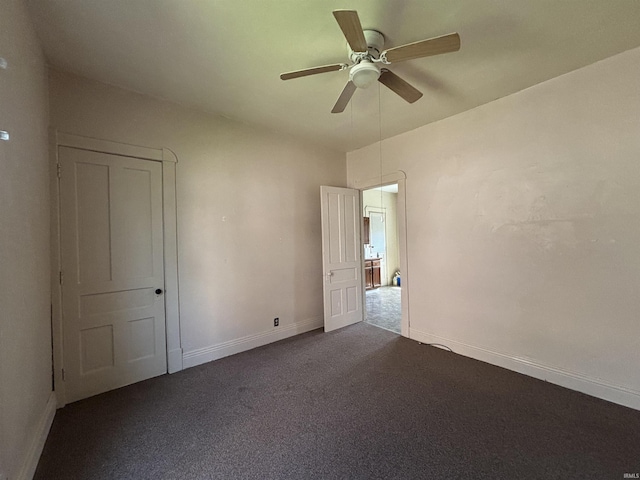 empty room with dark carpet, ceiling fan, and baseboards