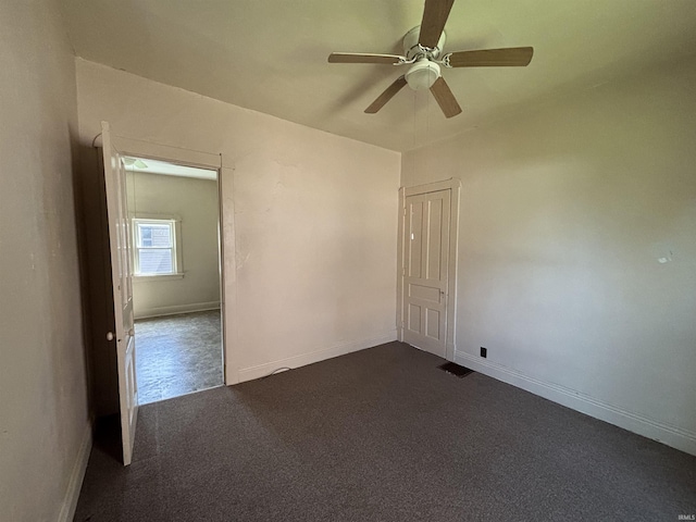 unfurnished room with baseboards, a ceiling fan, visible vents, and dark carpet