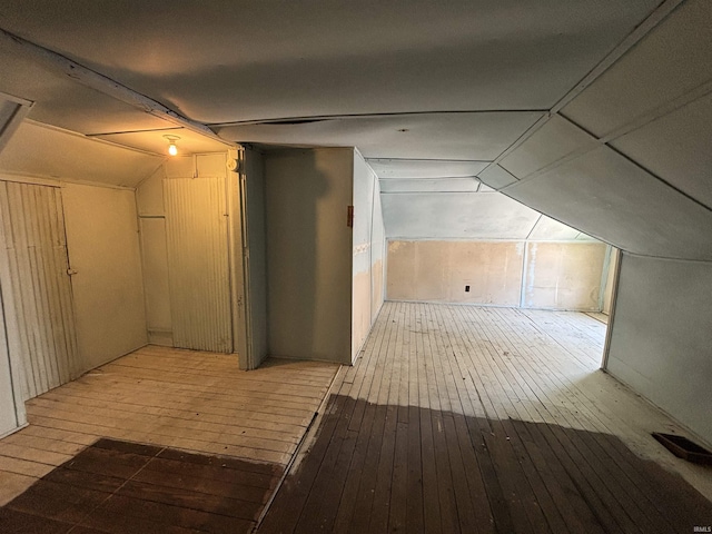 additional living space with vaulted ceiling, hardwood / wood-style floors, and visible vents