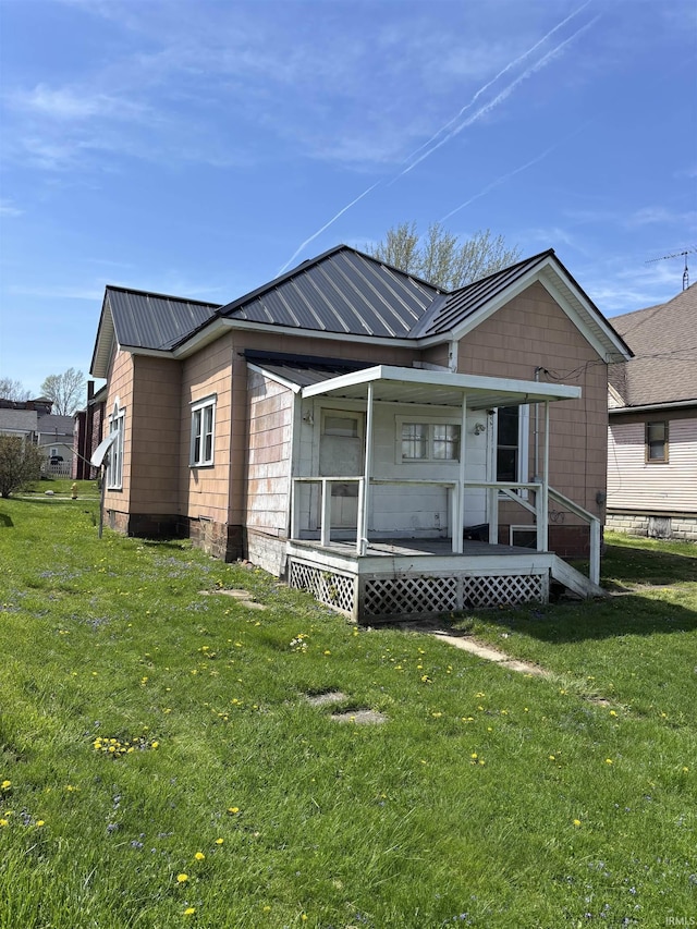 back of property with a porch, a yard, and metal roof