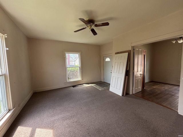 empty room featuring dark carpet, baseboards, and a ceiling fan
