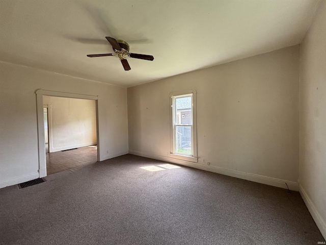 carpeted empty room featuring visible vents, baseboards, and ceiling fan