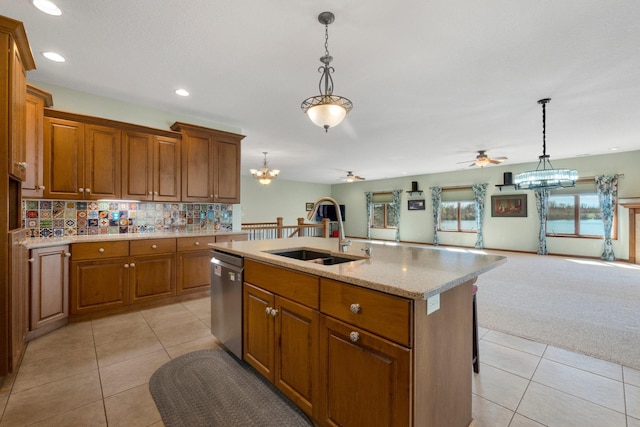 kitchen with dishwasher, a sink, brown cabinetry, open floor plan, and ceiling fan with notable chandelier