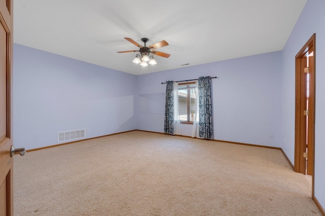 carpeted spare room with visible vents, a ceiling fan, and baseboards