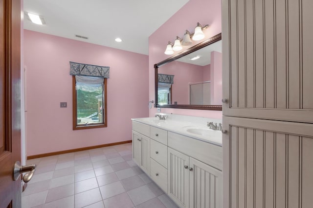 bathroom featuring baseboards, a sink, visible vents, and double vanity