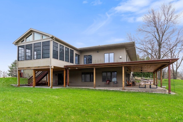back of house featuring a lawn, a sunroom, a patio area, and stairs