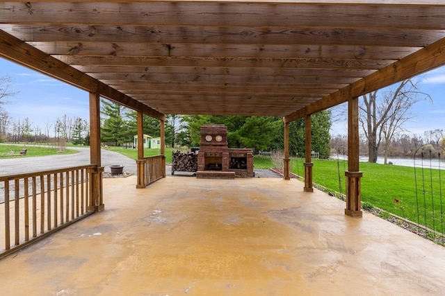 view of patio featuring a carport, a pergola, an outdoor fireplace, and a water view