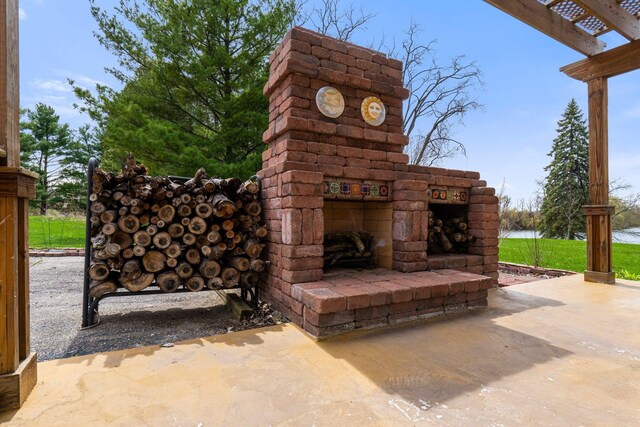 view of patio / terrace featuring a water view and an outdoor stone fireplace