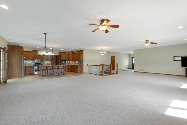 living room with ceiling fan with notable chandelier, visible vents, and light colored carpet
