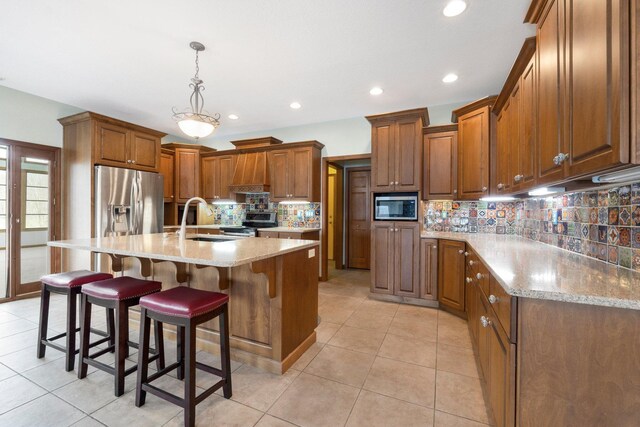 kitchen with brown cabinets, a sink, tasteful backsplash, appliances with stainless steel finishes, and a breakfast bar area