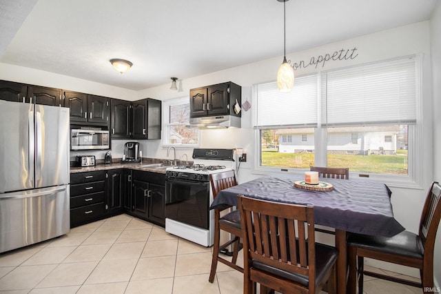 kitchen featuring light tile patterned floors, under cabinet range hood, a sink, and appliances with stainless steel finishes