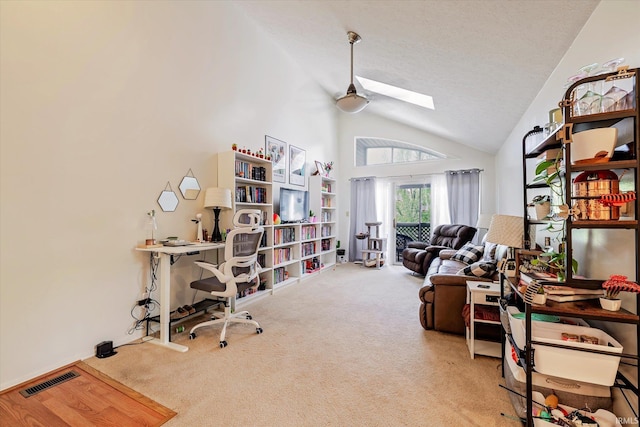 office space featuring visible vents, ceiling fan, high vaulted ceiling, carpet flooring, and a skylight