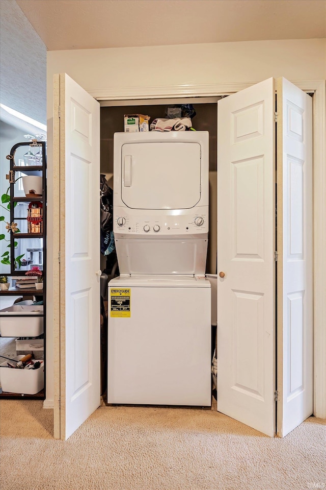 laundry room with light colored carpet, stacked washer and dryer, and laundry area
