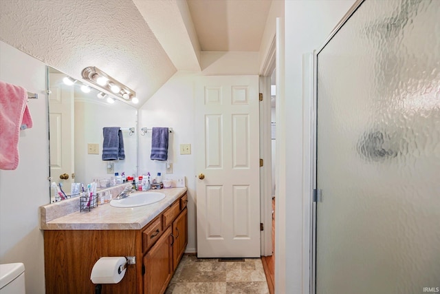 full bath with vanity, a shower stall, toilet, and stone finish flooring