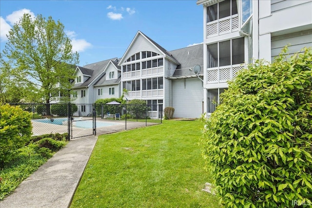 rear view of property with a yard, fence, and a fenced in pool