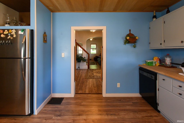 kitchen featuring baseboards, wood finished floors, black dishwasher, and freestanding refrigerator