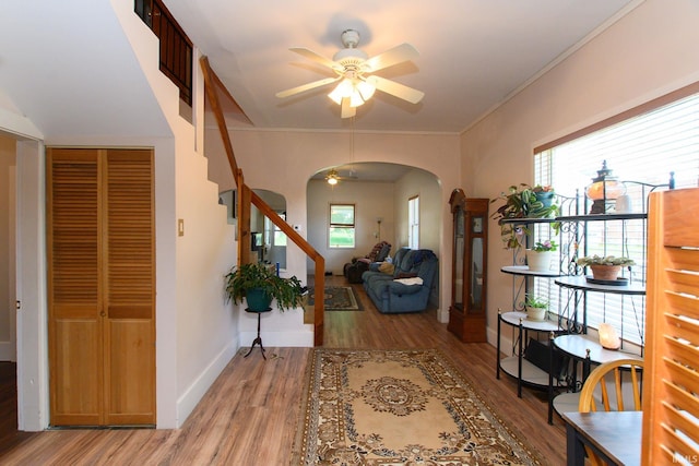 foyer entrance featuring arched walkways, light wood-style flooring, a ceiling fan, and plenty of natural light