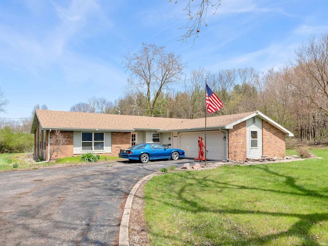 view of front of property featuring an attached garage, aphalt driveway, brick siding, and a front yard
