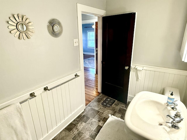 bathroom featuring a wainscoted wall, stone finish floor, and a sink
