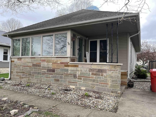 view of home's exterior featuring roof with shingles and covered porch
