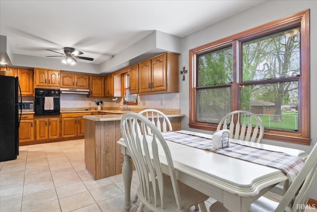 kitchen featuring black appliances, brown cabinets, and a wealth of natural light