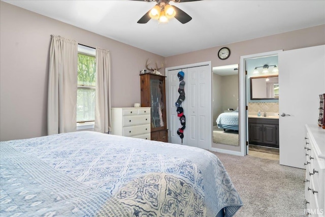 carpeted bedroom featuring a ceiling fan, ensuite bathroom, and a closet
