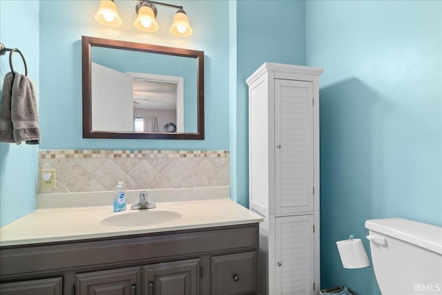 bathroom featuring vanity, backsplash, a closet, and toilet