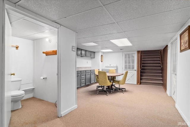 dining area featuring light colored carpet, a drop ceiling, and stairway