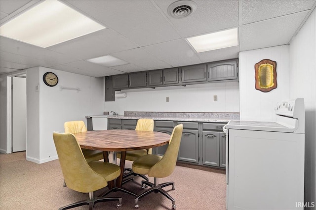 dining area with light carpet, a paneled ceiling, visible vents, and washer / dryer