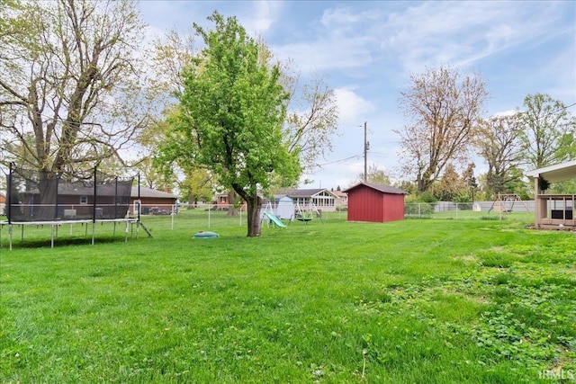 view of yard featuring a storage shed, a trampoline, an outbuilding, and a fenced backyard