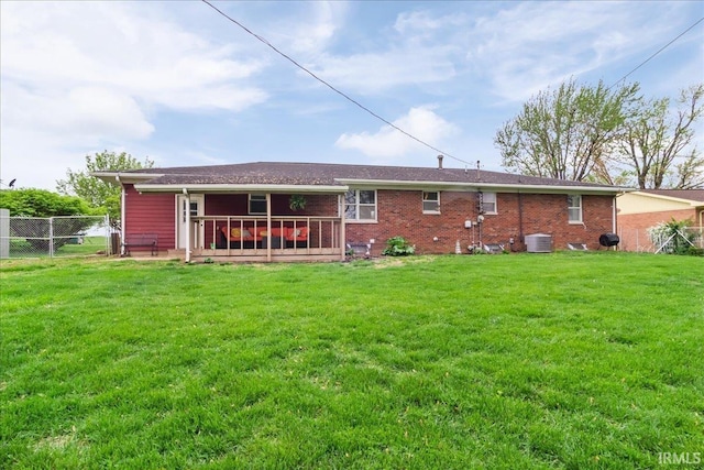back of property featuring fence, a lawn, brick siding, and cooling unit