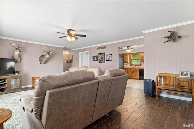living room with ornamental molding, dark wood finished floors, visible vents, and ceiling fan