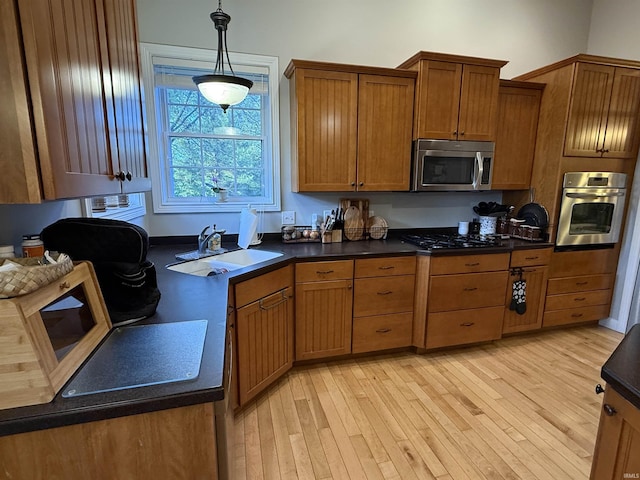 3201 E Kristen Ct, Bloomington, IN 47401 - kitchen with stainless steel appliances, a sink, light wood-type flooring, brown cabinetry, and hanging light fixtures