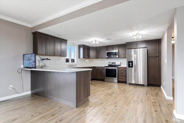 1689 E 550 Rd S, Peru, IN 46970 - kitchen with stainless steel appliances, a peninsula, light wood-style flooring, dark brown cabinets, and ornamental molding