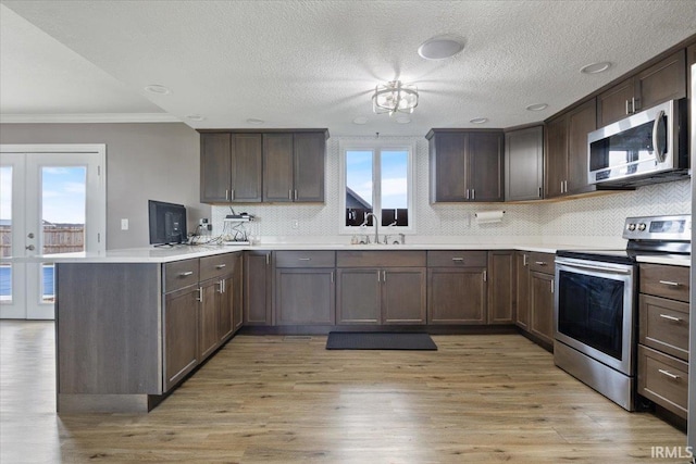 1689 E 550 Rd S, Peru, IN 46970 - kitchen featuring a sink, stainless steel appliances, light countertops, a peninsula, and ornamental molding