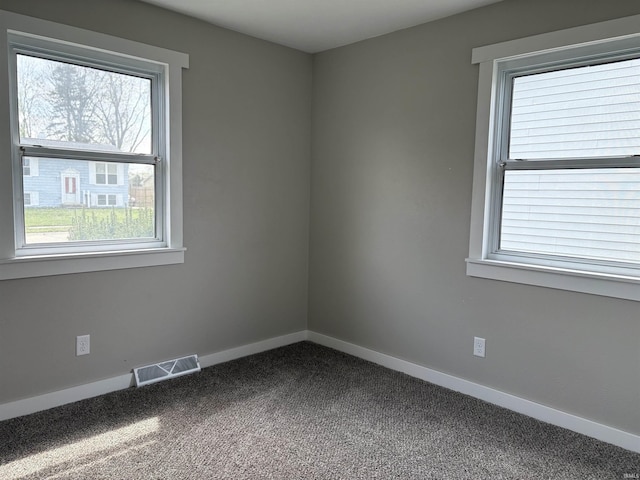 carpeted spare room featuring baseboards and visible vents