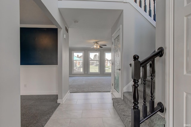 entrance foyer featuring baseboards, visible vents, light colored carpet, a ceiling fan, and stairs