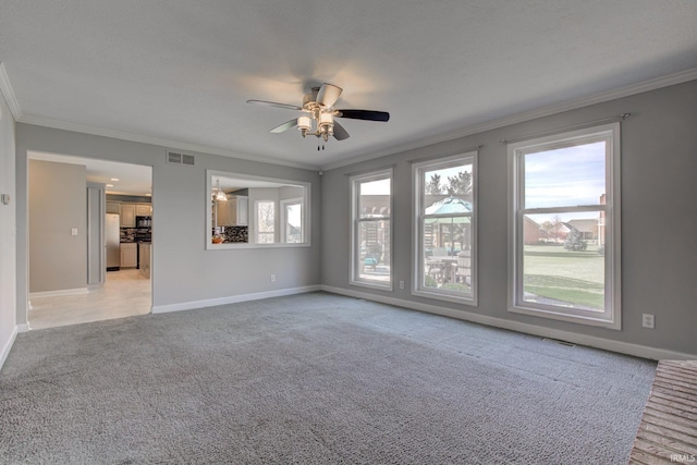 unfurnished living room featuring plenty of natural light, light carpet, visible vents, and ornamental molding
