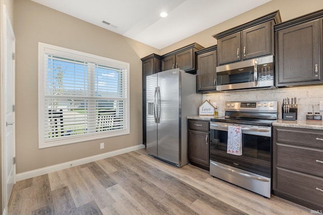 kitchen featuring stainless steel appliances, visible vents, dark brown cabinetry, light wood-style floors, and decorative backsplash