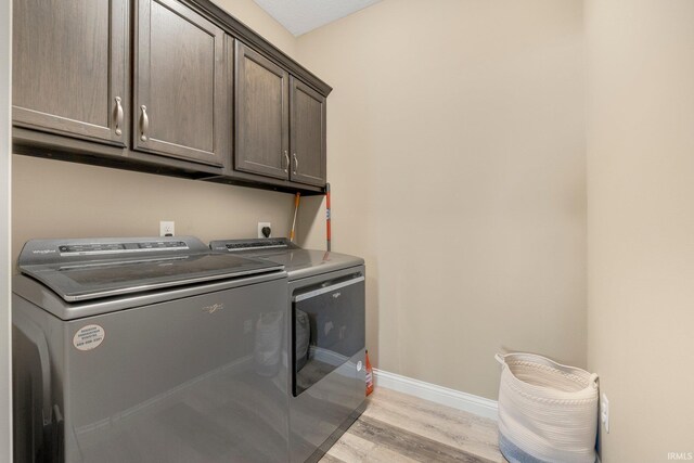 laundry area with baseboards, independent washer and dryer, light wood-style floors, and cabinet space