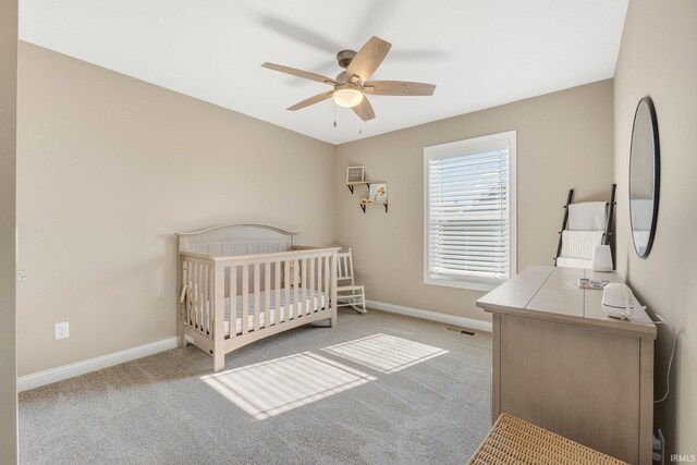 bedroom with a nursery area, carpet floors, a ceiling fan, and baseboards