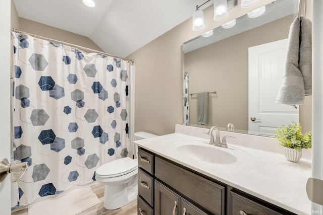 bathroom featuring lofted ceiling, toilet, vanity, and wood finished floors
