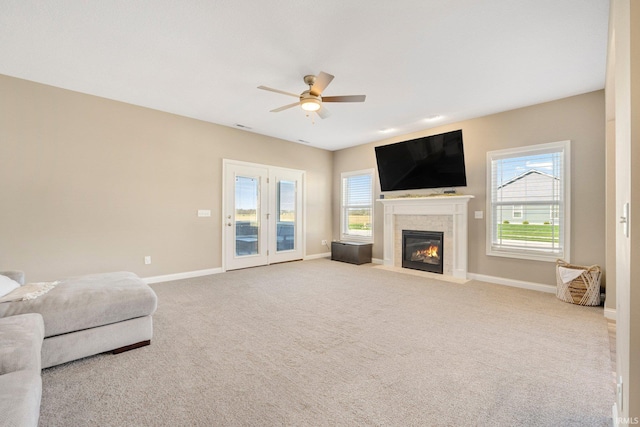 unfurnished living room with a fireplace with flush hearth, plenty of natural light, a ceiling fan, and baseboards